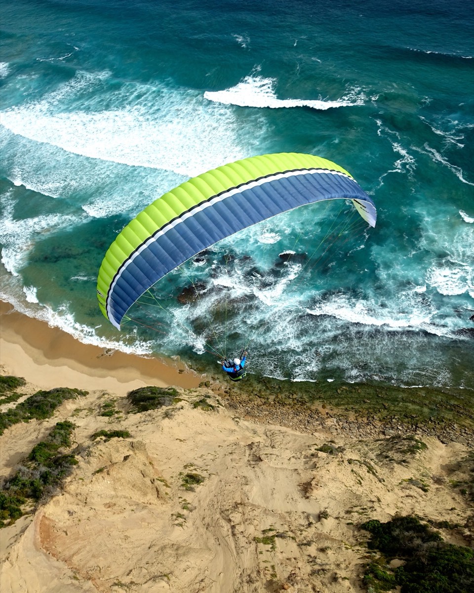 Paraglider boven een kustlijn, gezien van boven